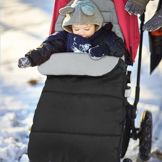 Bebe bien au chaud dans une chanceliere noire pour poussette.
