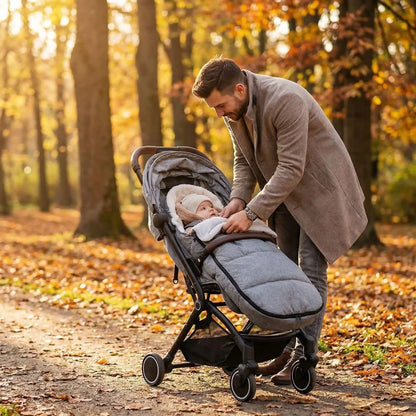 
Père promenant son bébé dans une chancelière universelle pour poussette grise dans un parc aux couleurs d’automne.