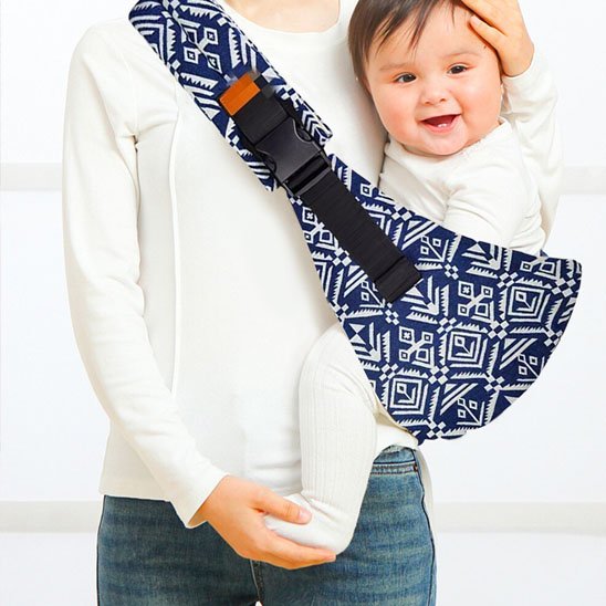 Porte bebe bandoulière bleu à motifs avec bébé porté sur la hanche