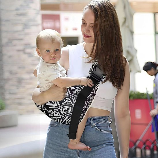 Porte bebe bandoulière noir et blanc avec bébé blond, extérieur