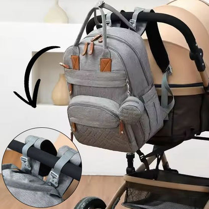 Sac à langer gris accroché à une poussette avec crochets de fixation.