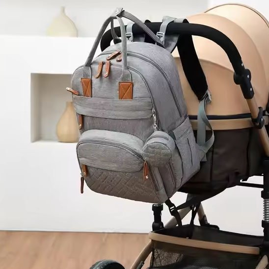 Sac à langer elegant gris, suspendu à une poussette beige