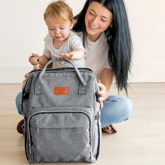 Maman et bébé avec un sac à dos à langer gris moderne fabriqué en tissu  imperméable.