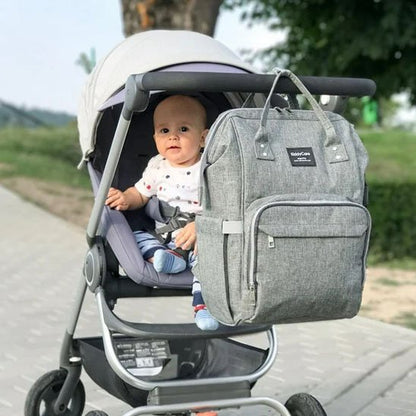 sac à dos à langer gris élégant et spacieux accroché à une poussette.