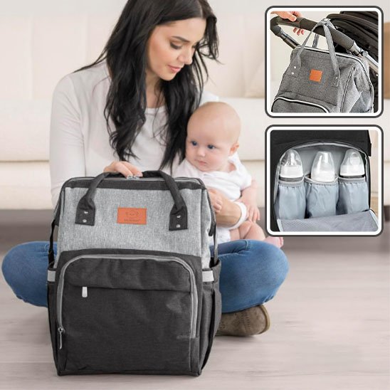 Maman assise avec son bébé et un sac à langer gris noir, avec compartiments pour biberons et accroches pour poussette.